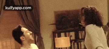 a man and a woman are standing next to each other in a bedroom .