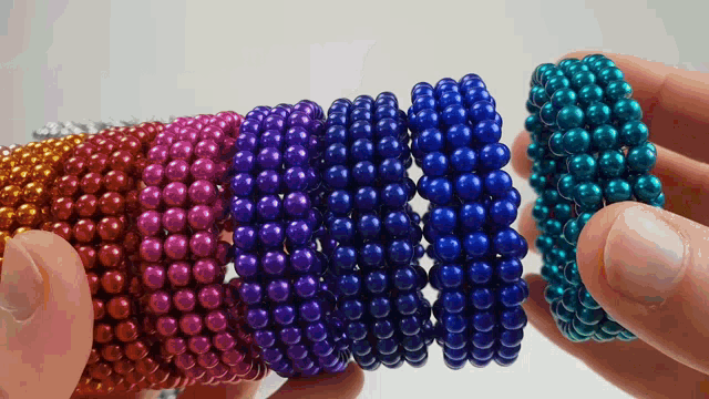 a person holding a bunch of different colored beads in their hands