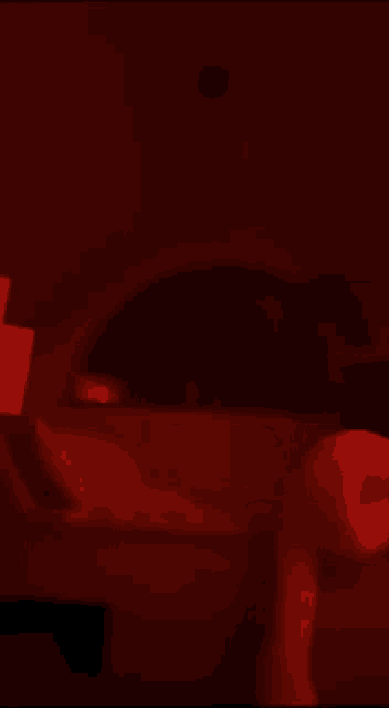a person laying on a couch in a dark room with a red light behind them