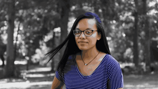 a young woman wearing glasses and a blue striped shirt
