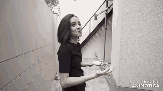 a woman in a black shirt is standing next to a wall with the words made in animotica on the bottom