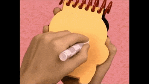 a person is writing on a notebook with a marker