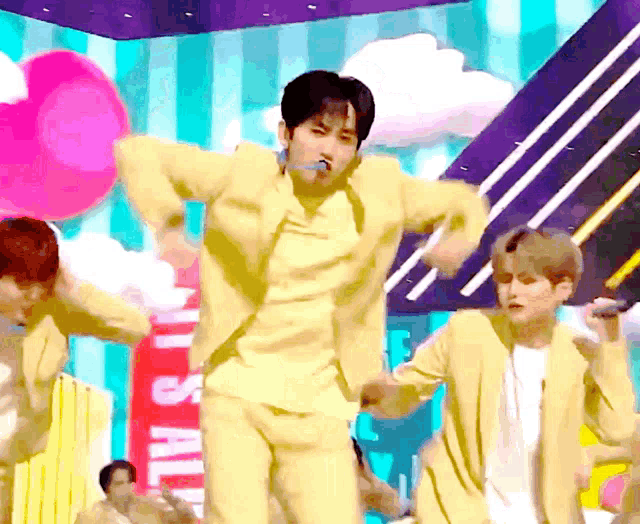a man in a yellow suit is dancing on a stage in front of a sign that says it 's all