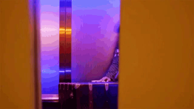 a person is standing in an elevator with a suitcase in front of a window .