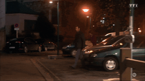 a man walking in a parking lot with a sign that says tfi