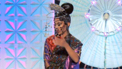 a woman in a kimono with a bun on her head is standing on a stage with umbrellas in the background .