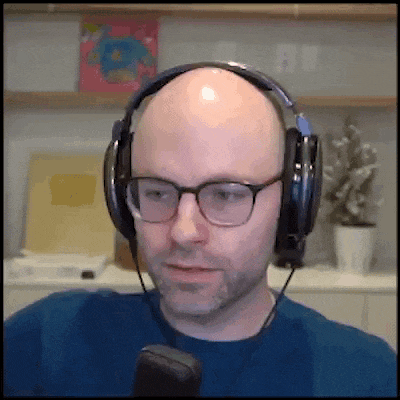 a bald man wearing glasses and headphones is looking at the camera
