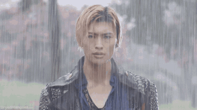 a man standing in the rain with the website dryedmangooz.com visible in the background