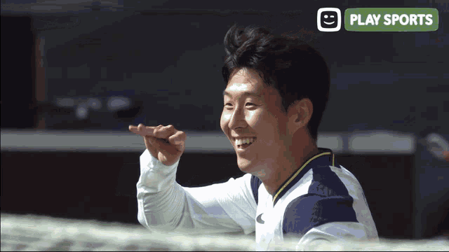 a man is smiling in front of a play sports banner