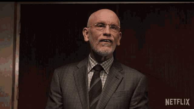 a man in a suit and tie is clapping in front of a netflix sign