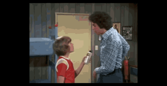 a man and a boy are standing next to each other in a bedroom