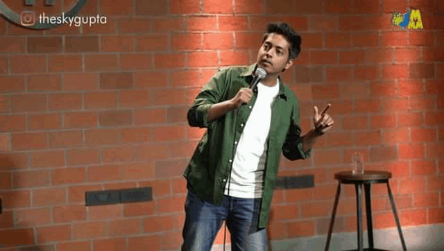a man in a green shirt is standing in front of a microphone .