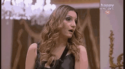 a woman is standing in front of a chandelier in a room on a tv screen .