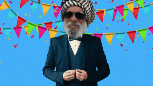 a man wearing a suit and a turban is standing in front of colorful flags