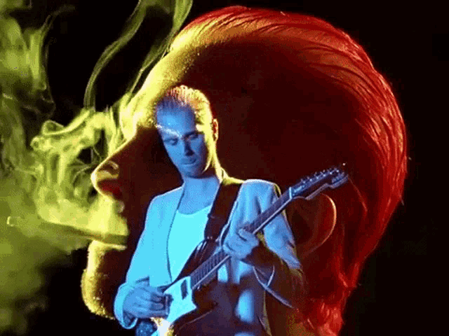 a man with red hair is smoking a cigarette while playing a guitar