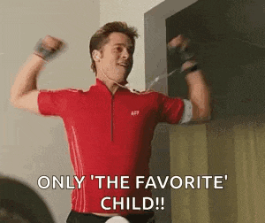 a man in a red shirt is flexing his muscles and says `` only the favorite child ! ''