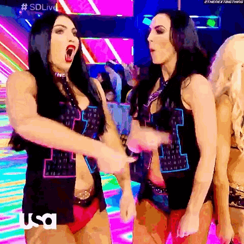 a couple of women are standing next to each other in a room with a rainbow background .
