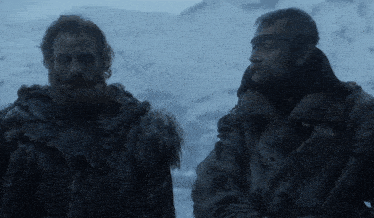 two men are standing in the snow and one has a beard