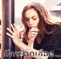 a woman is sitting down with her hands on a pole while eating a piece of food .