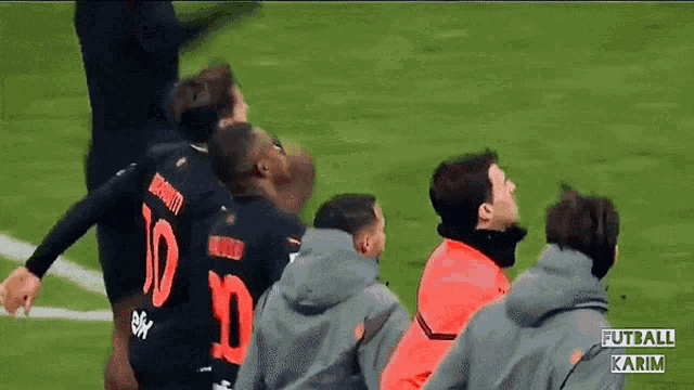 a soccer player with the number 10 on his back is surrounded by his teammates