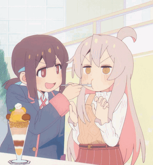 a girl is feeding another girl a spoon of food