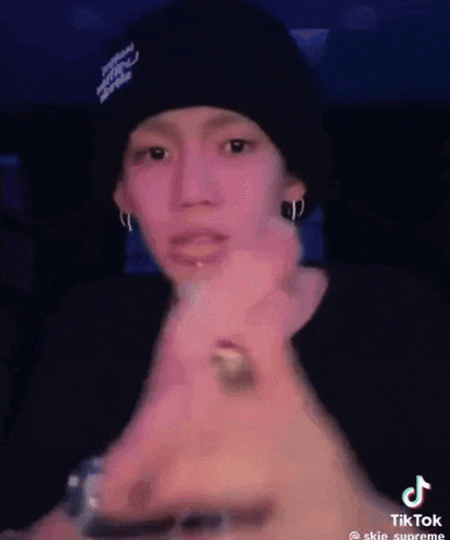 a young man wearing a black beanie and earrings is giving a thumbs up .
