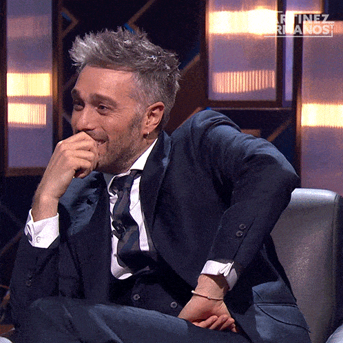 a man in a suit and tie is sitting in a chair with the words martinez hermanos written above him