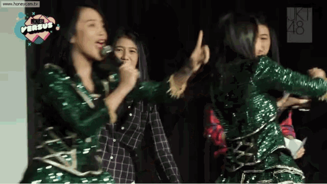 a group of girls are performing on a stage with the website www.here-cam.tv at the top