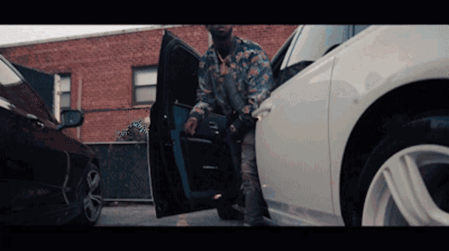 a man in a floral shirt is getting out of a white car