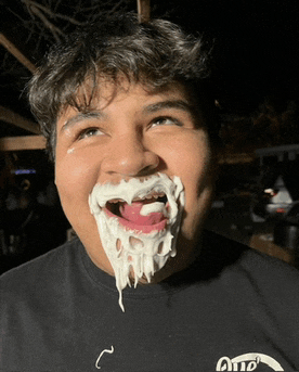 a man with whipped cream on his face is wearing a black shirt that says ohio