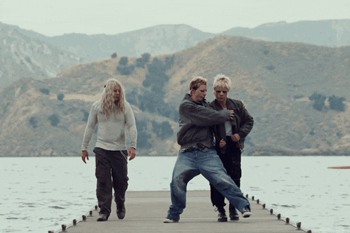 a group of people standing on a dock near a lake