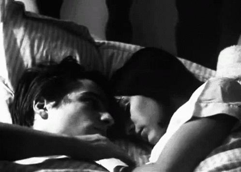 a man and a woman are laying in bed together .
