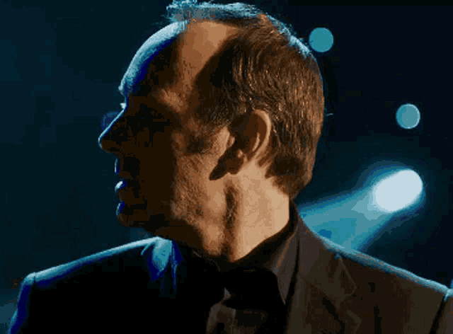 a man in a suit and tie is standing in front of blue lights