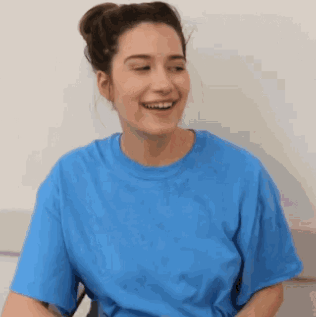 a woman wearing a blue t-shirt is smiling