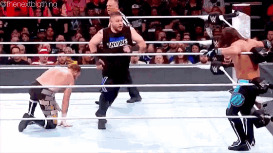 a group of wrestlers are wrestling in a ring while a crowd watches .