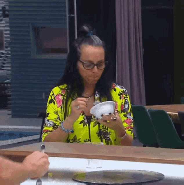 a woman sitting at a table with a bowl of food in her hand