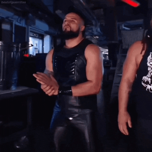a man with a beard wearing black leather pants is clapping his hands