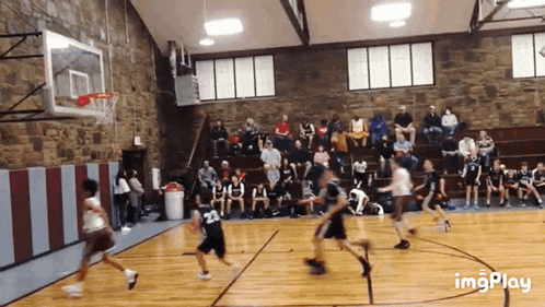 a basketball game is being played in a gym with a crowd watching