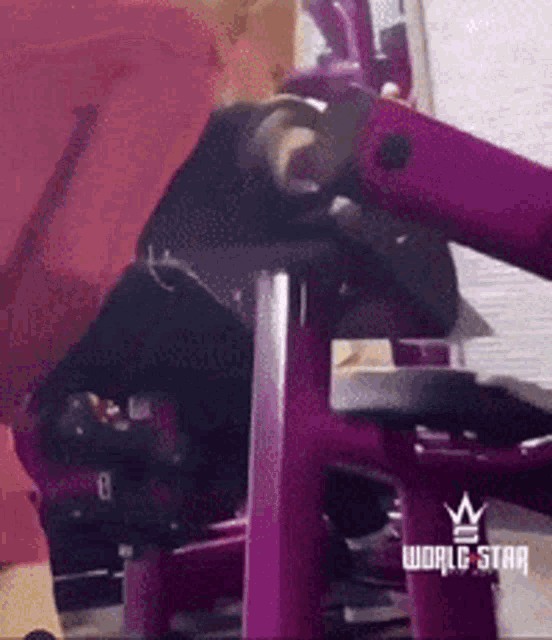 a person is using a purple machine in a gym with world star written on it .