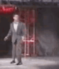 a blurry picture of a man in a suit standing in front of a red sign .