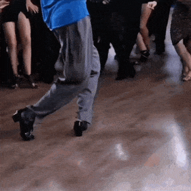 a man in a blue shirt is dancing with a group of people