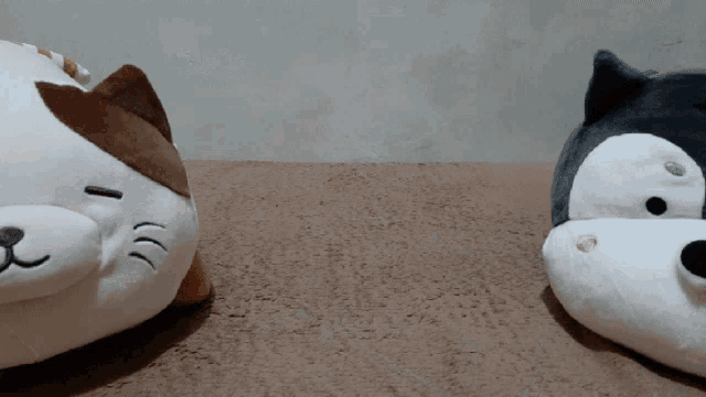a stuffed cat and a stuffed dog are laying on a brown surface