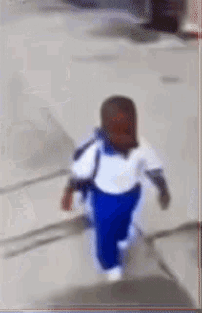 a blurry picture of a child in blue pants and a white shirt walking down stairs .