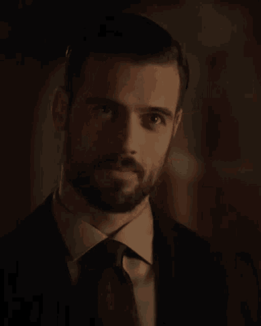 a man with a beard is wearing a suit and tie and smiling