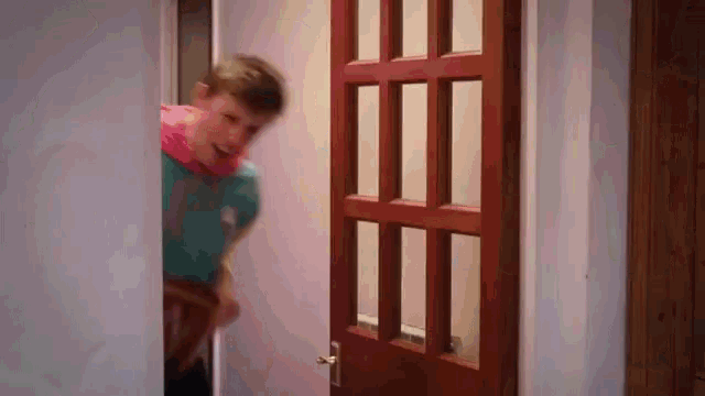 a man in a blue shirt is standing in front of a brown door