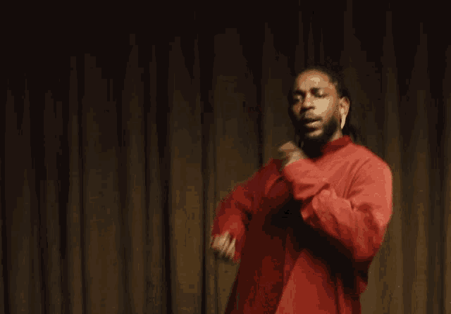 a man wearing a red shirt and earrings looks down