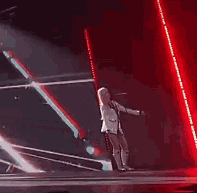 a woman is standing on a stage holding a microphone and singing into it .