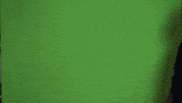 a man in a black hoodie stands in front of a green background