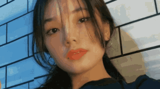 a close up of a woman 's face against a blue brick wall .