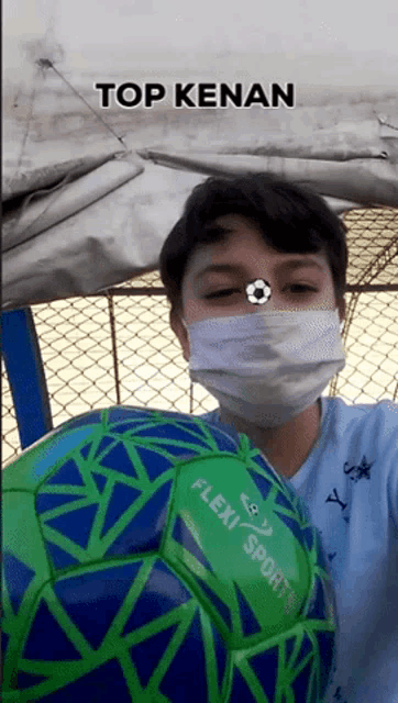 a boy wearing a mask is holding a flexi sport soccer ball in front of his face